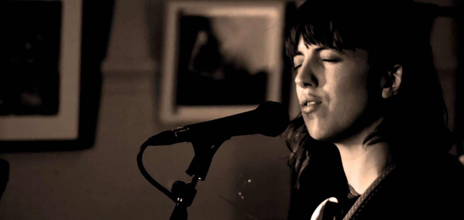 A woman singing passionately into a microphone, capturing a musical moment with emotional expression, ideal for a sound archive of music, live performances, and artistic audio content.