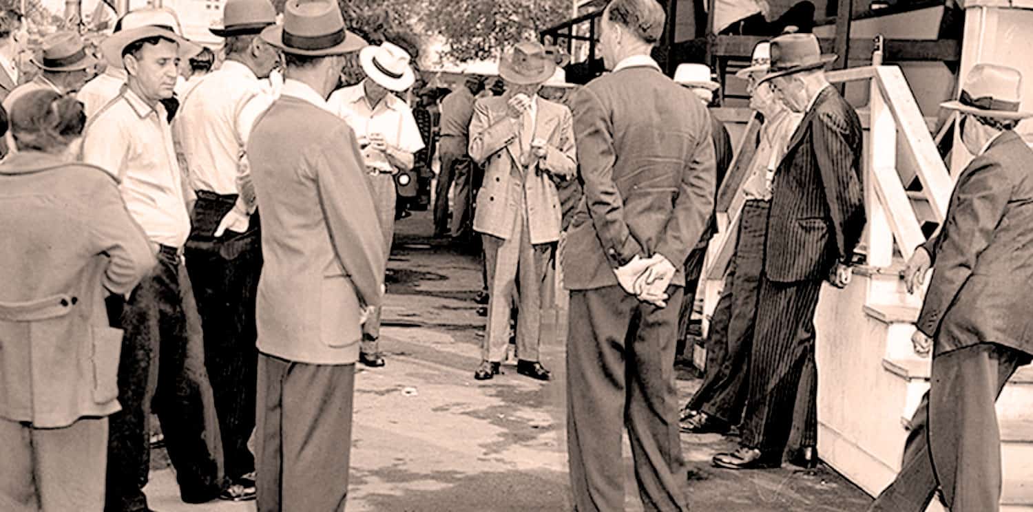 A black and white vintage photo of people gathered outdoors, dressed in mid-20th century clothing, possibly at a historical event or news gathering, reflecting a sound archive of history, news, and music.