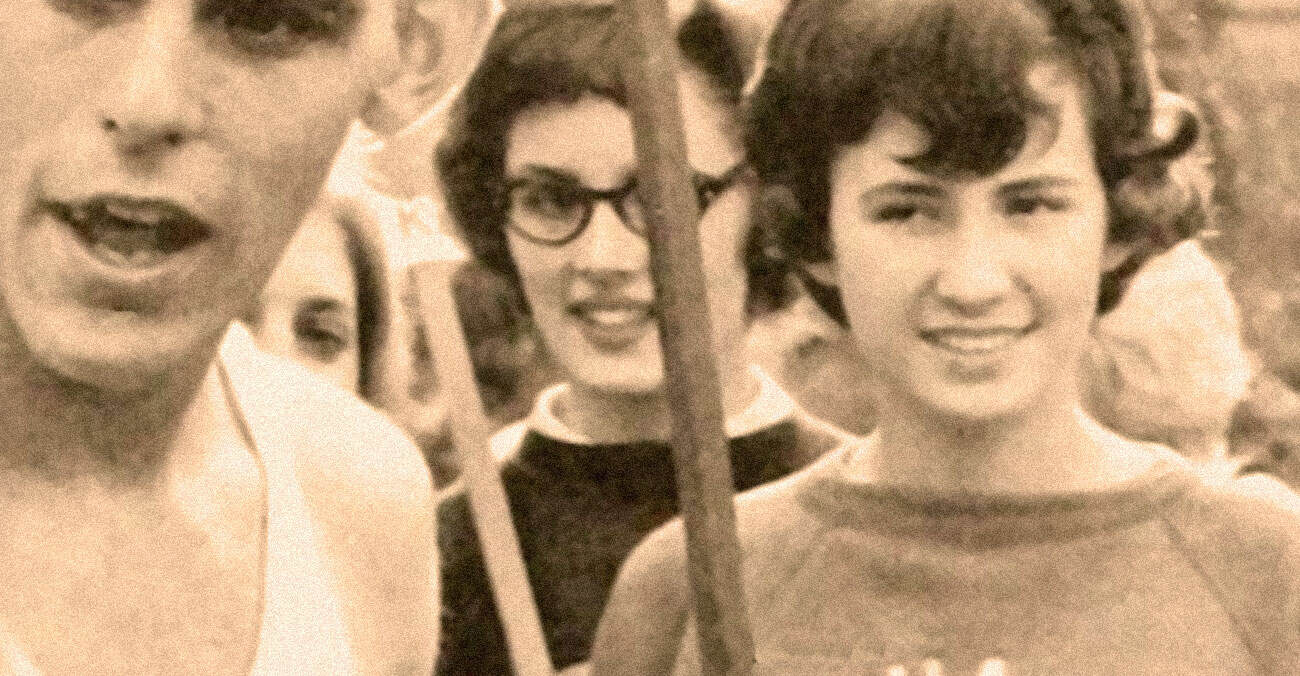 Vintage black and white photo of young people smiling at a protest or rally, showcasing community activism and historical moments, capturing a sense of unity and social engagement.