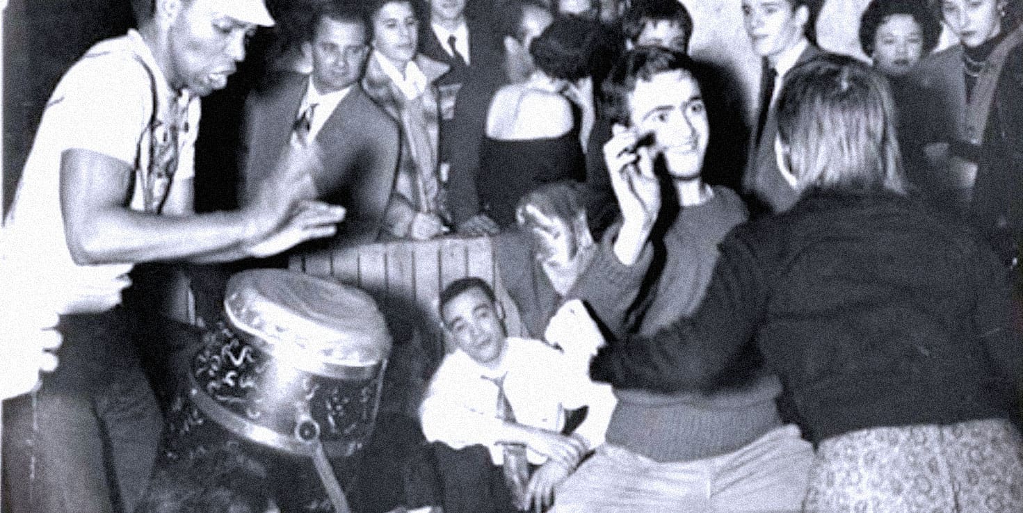 A group of young people gathered in a social setting, engaging in conversations and activities, capturing a nostalgic moment possibly from the mid-20th century, highlighting historical music and social trends.