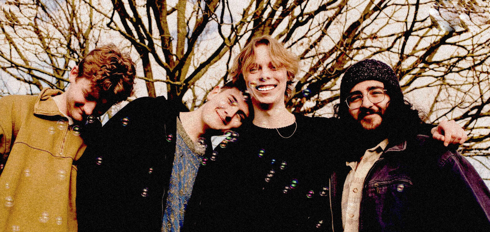 Colorful indie band members smiling outdoors, representing music history and youth culture, captured for archival purposes on Past Daily sound archive website.