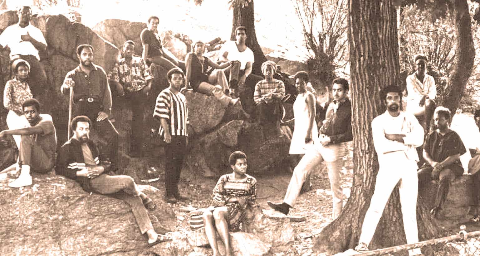African American family gathering outdoors around a large tree with rocks, embracing community, history, and cultural heritage – archival sound archive of news, history, and music from Past Daily.