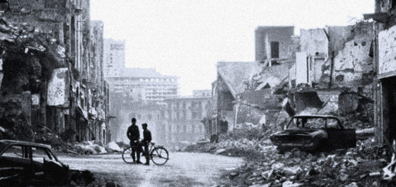 Ruined urban landscape with damaged buildings and abandoned cars from wartime devastation, showing two silhouetted figures with bicycles in the foreground, symbolizing the aftermath of conflict.