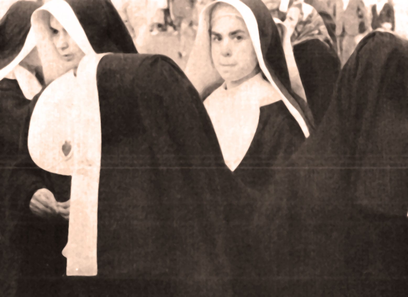 Nuns in traditional habits at a historical event, black and white photo capturing religious attire and solemn expressions for nostalgic archive content.