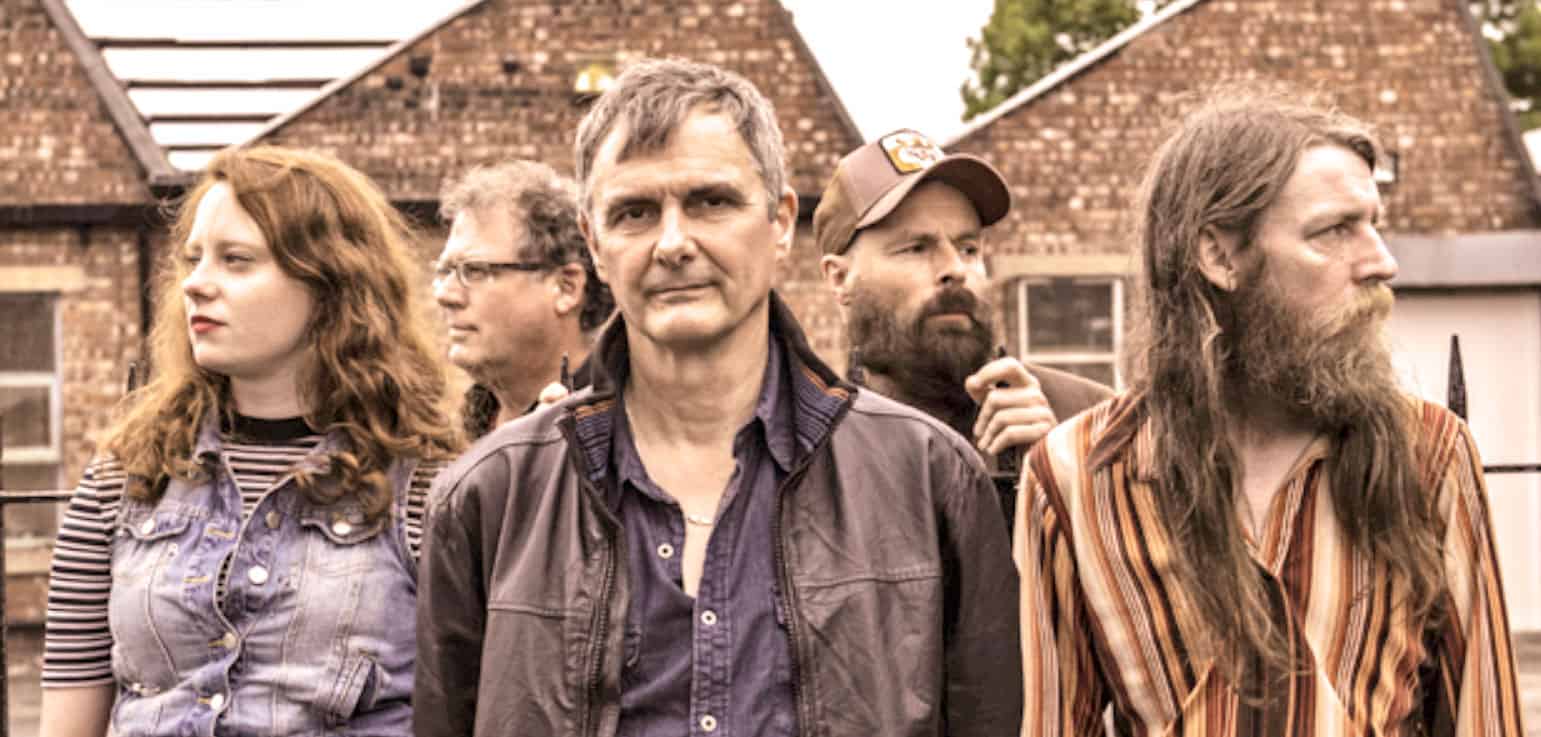 A sound archive of news, history, and music featuring a diverse group of people outdoors with a brick house in the background, highlighting vintage audio recordings and cultural history preservation.