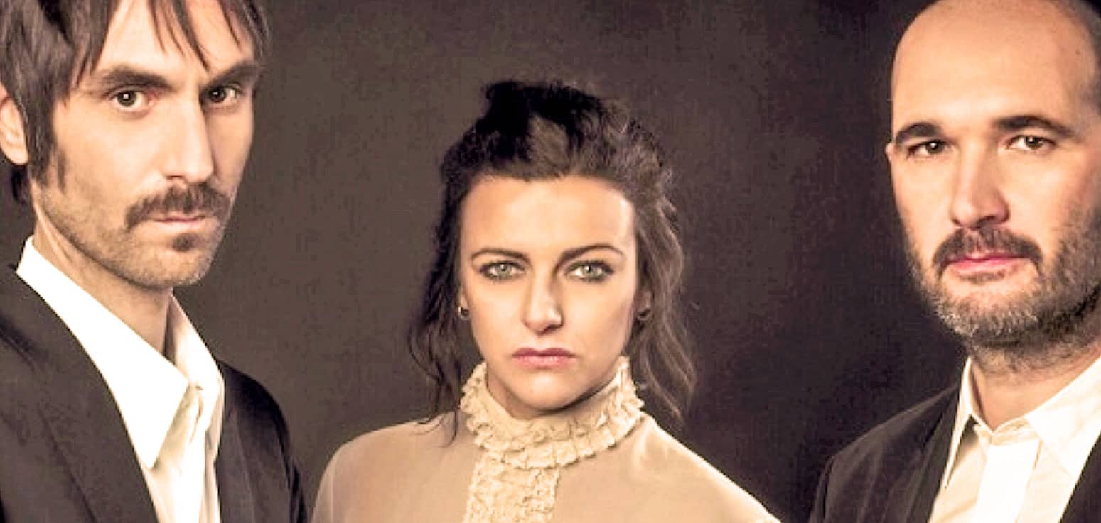Vintage band members portrait, classic music promotional image, featuring male and female musicians with serious expressions, highlighting history, news, and music archives.