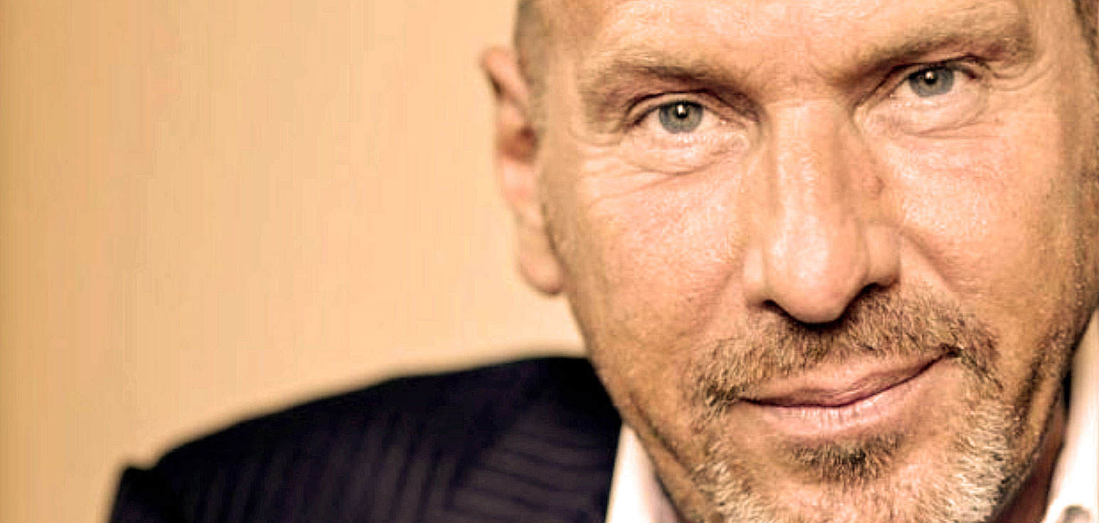 Close-up of a mature man with blue eyes and a light beard, representing historical news and music archives.