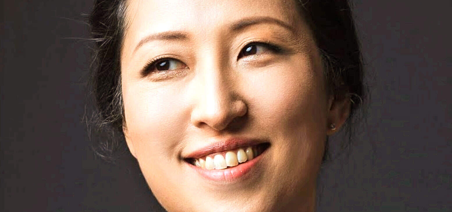 Close-up portrait of an Asian woman with a friendly smile and brown eyes, showcasing natural beauty and expressive features, suitable for a feature on news, history, and music sound archives.