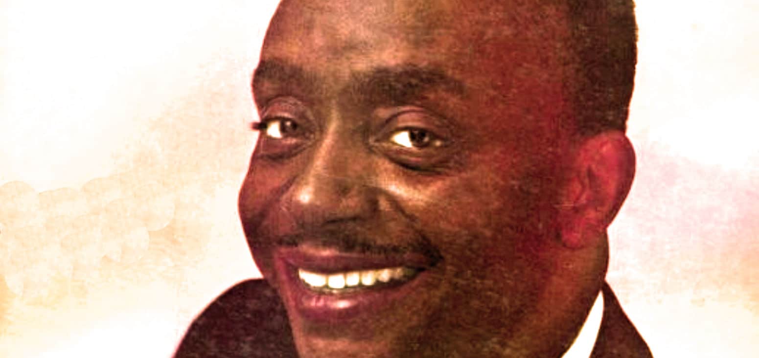 African American man smiling in a vintage photo, representing historical figures in news, music, and cultural archives.