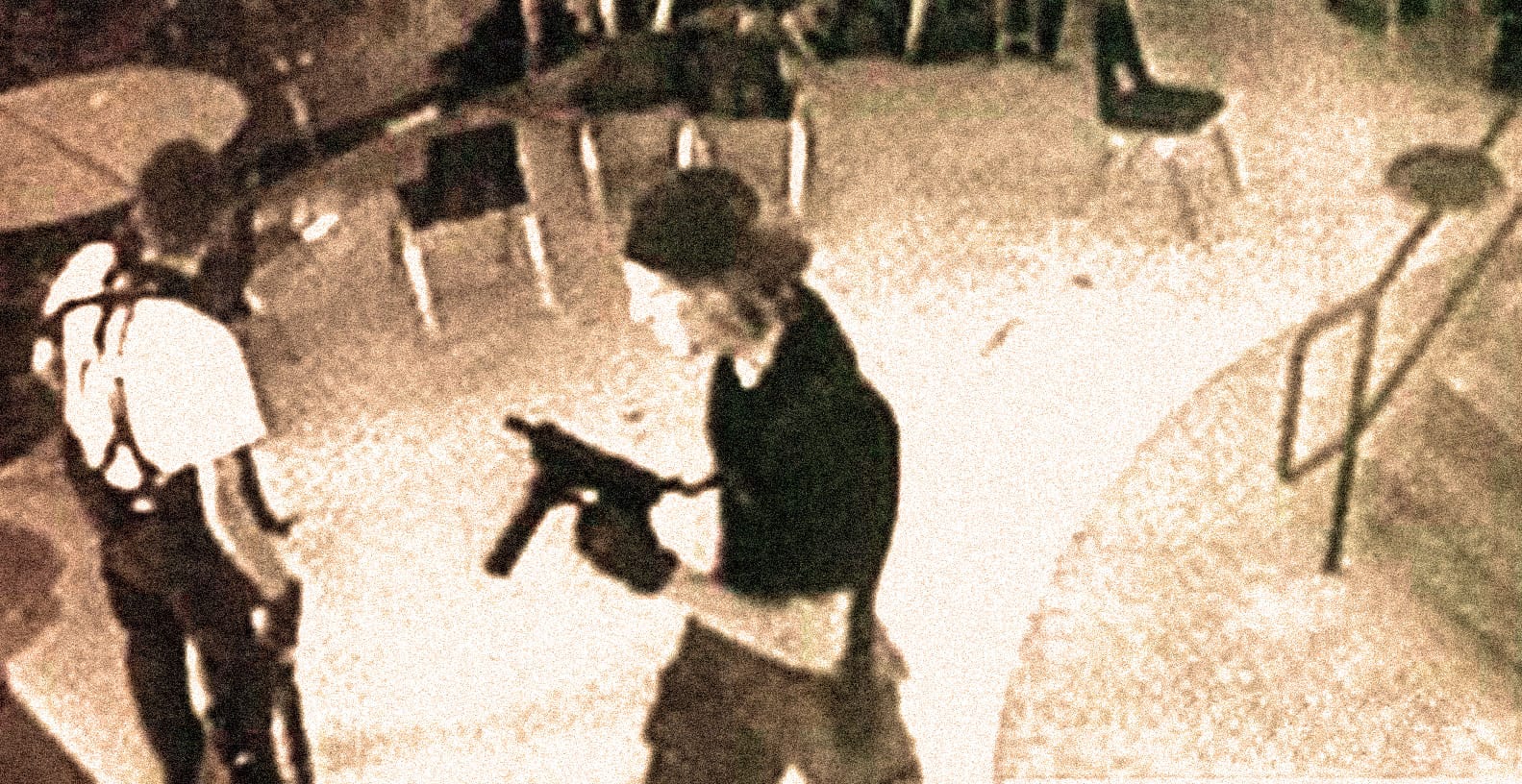 Gun-wielding man in dark clothing with curly hair standing outside at night, surveillance photo, security camera image, public safety, crime prevention, urban environment, nighttime scene, street security.