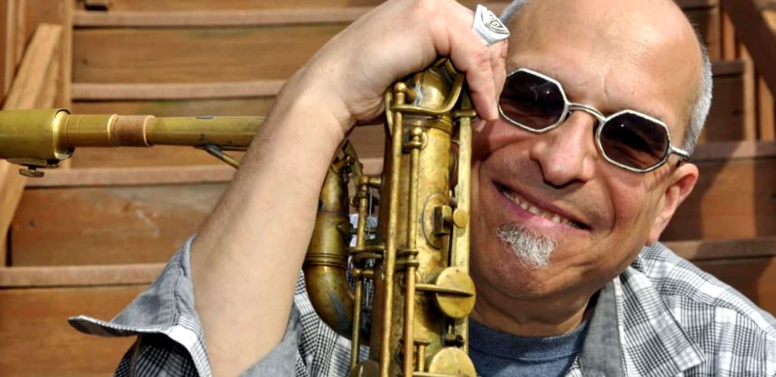 Vintage saxophone player smiling with sunglasses, capturing jazz and music history elements from Past Daily.