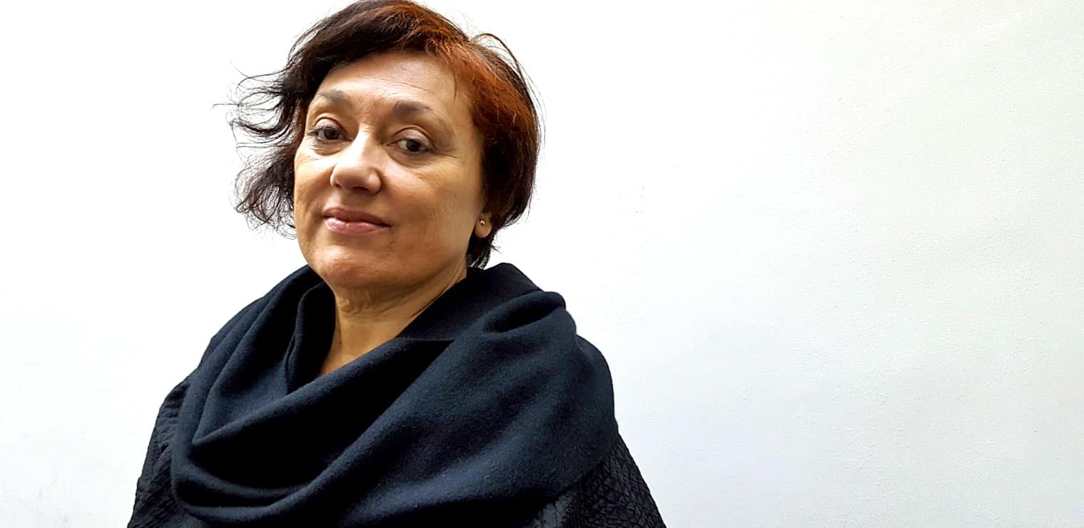 Elegant woman with short brown hair wearing a black scarf and jacket, representing archives of historical news, music, and media at Past Daily.