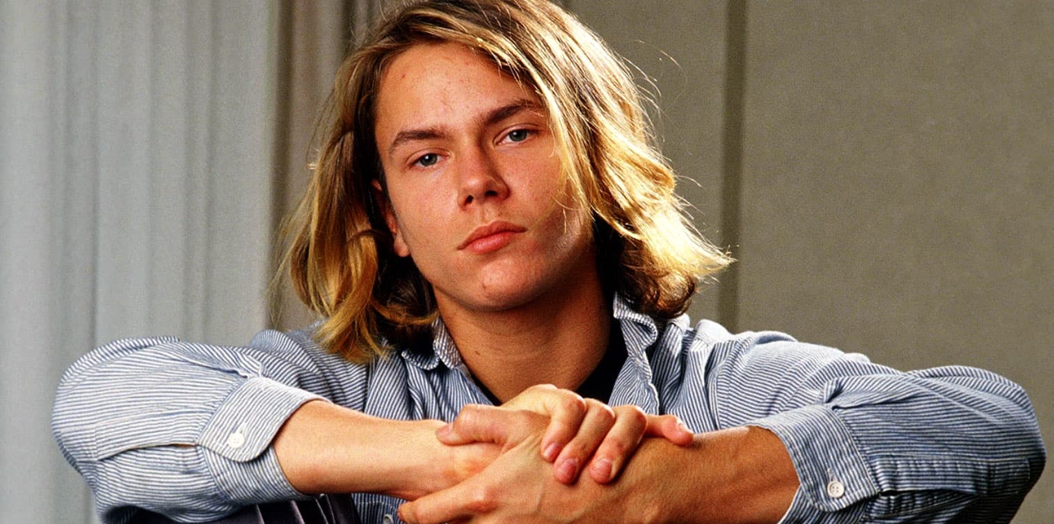 An archive image capturing a young man with long blonde hair and relaxed expression, symbolizing music, news, and history, for a sound archive website like Past Daily.