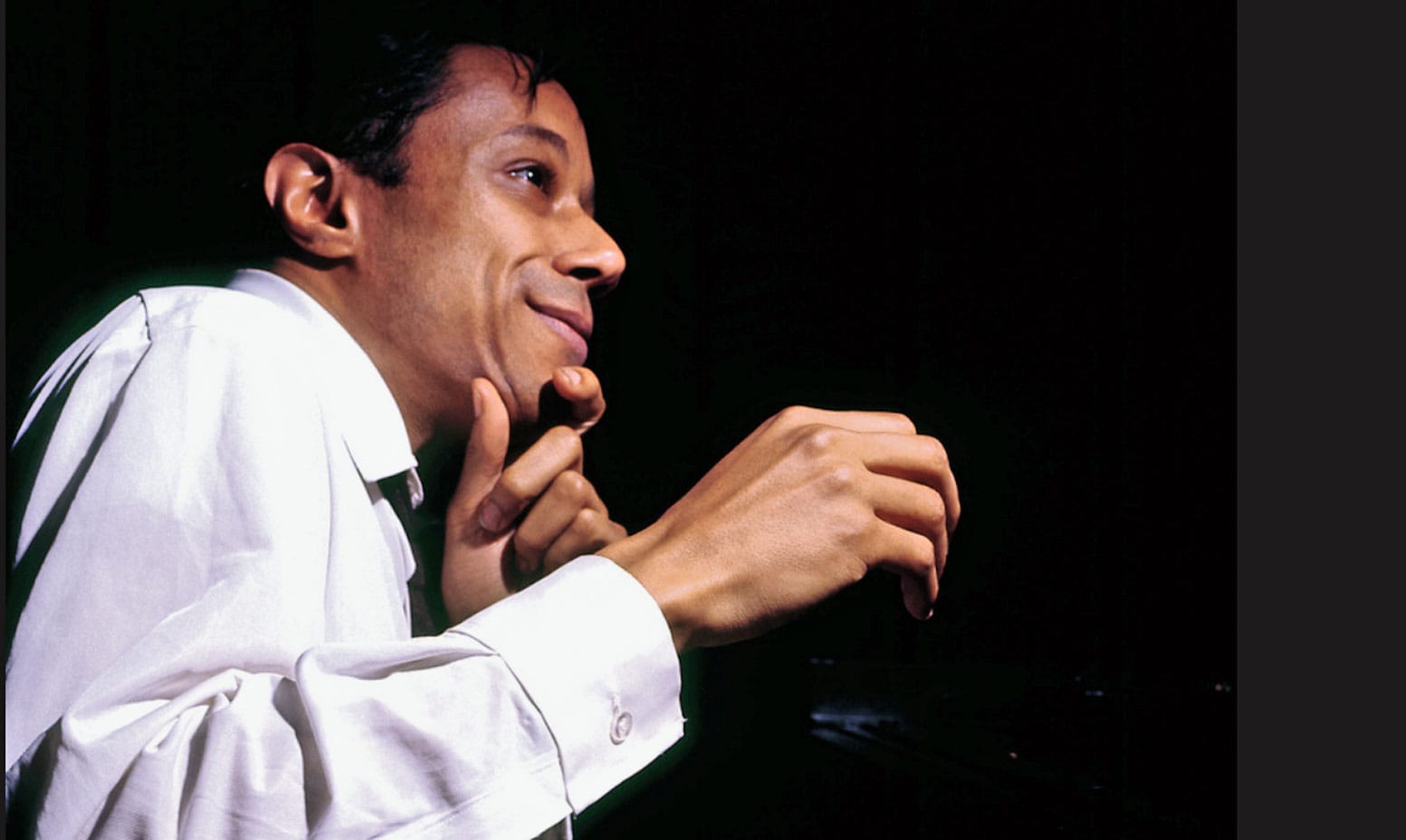 Vintage jazz musician playing piano, black background, nostalgic music archive related to news, history, and music collection.