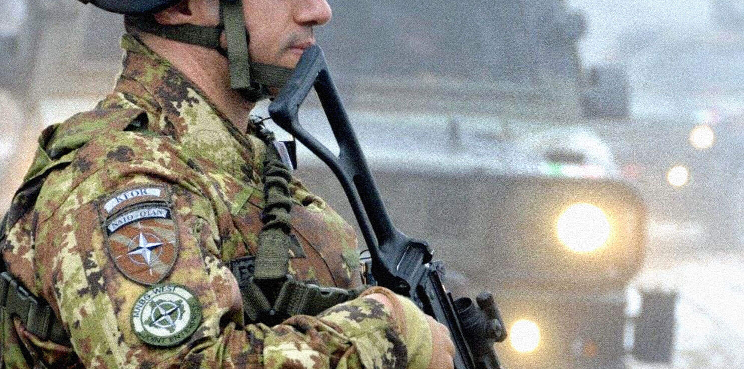 U.S. soldier in camouflage uniform holding tactical rifle during military operation, military gear and patches visible, background with smoke and lights, emphasis on defense and security.