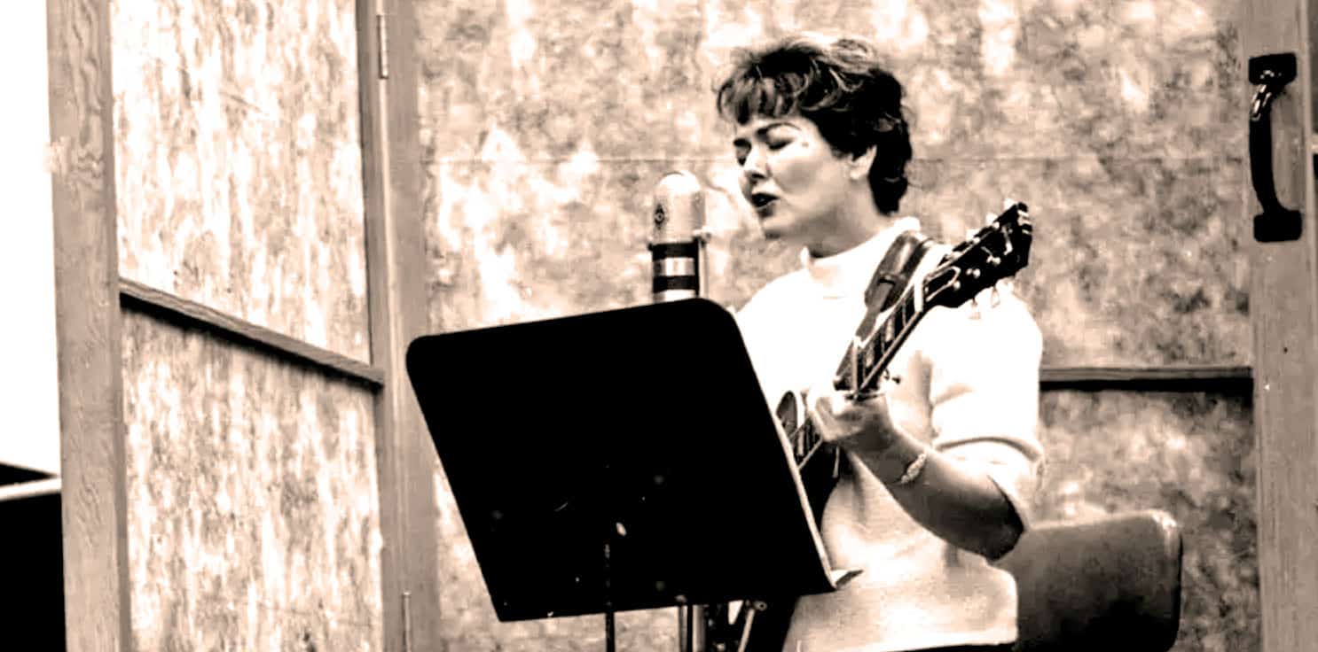 Guitar woman singing in recording studio, vintage style, black and white image, musician performing, passionate singer with guitar, recording session, music archive, historical music photo, Past Daily news and music archive.