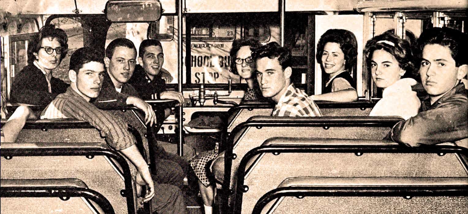 Vintage school bus with students, nostalgic black and white photo, young people riding public transportation, historical bus interior, classic transportation image.