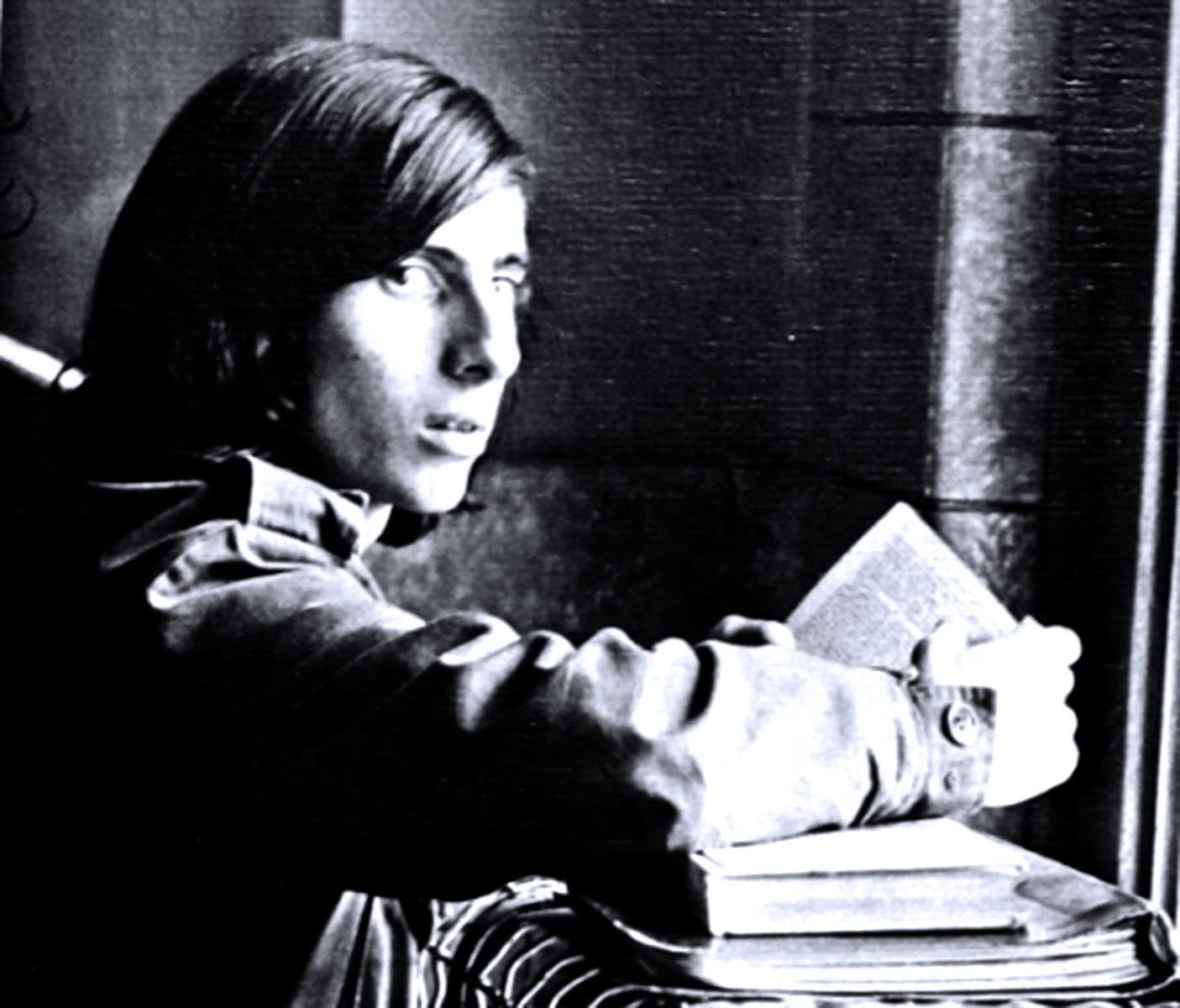 Teenage girl reading a book at a desk, black and white photo, vintage educational or nostalgic scene, reflective of history and cultural archives.
