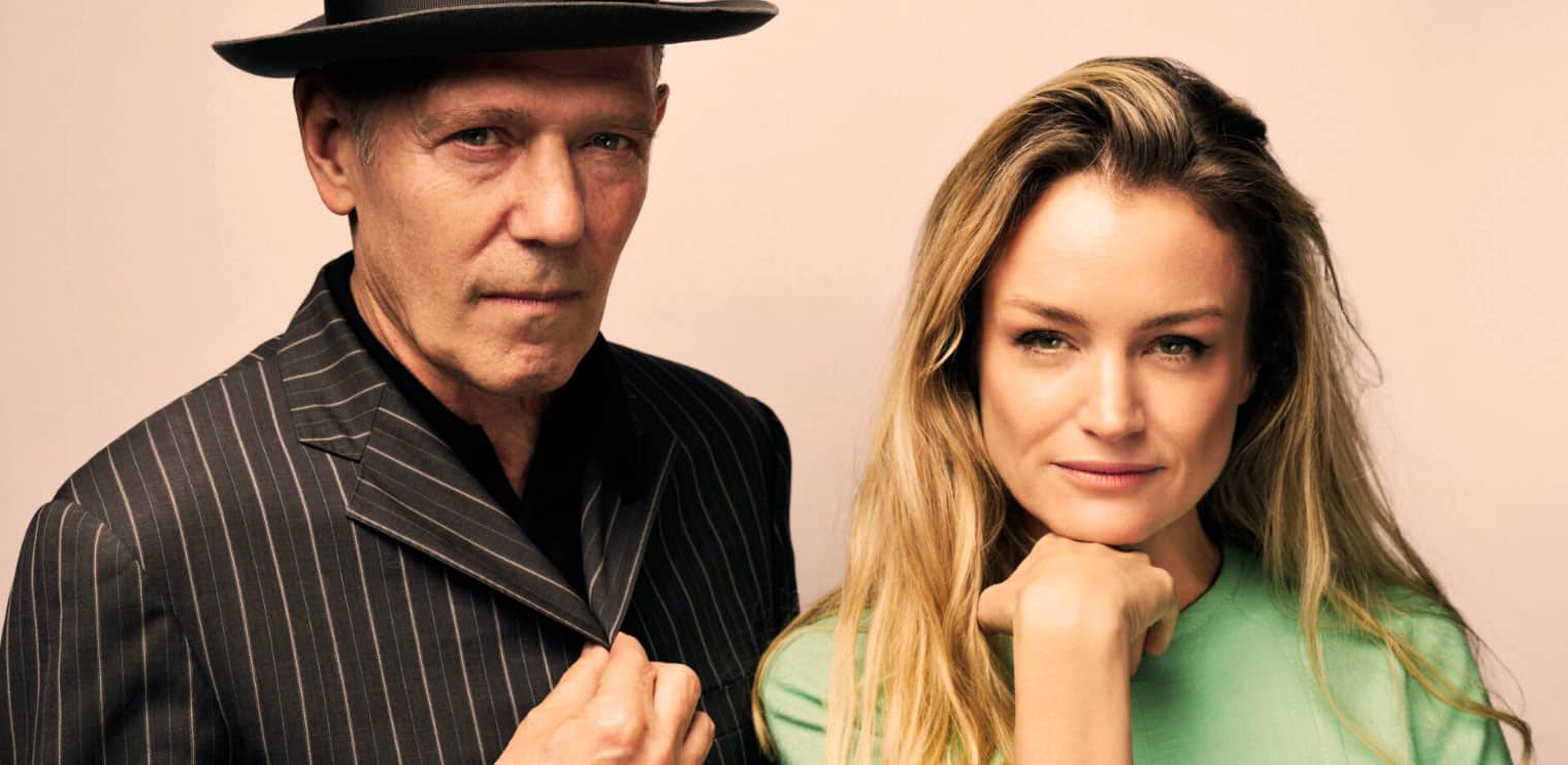A vintage man in a pinstripe suit and hat posing with a young woman in a green shirt, representing music, news, and history archives.