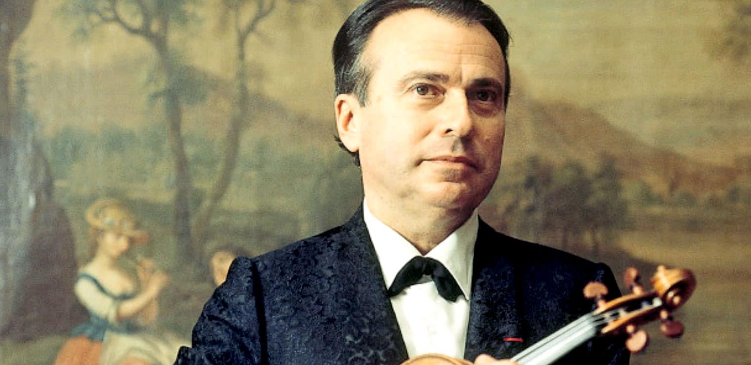 Close-up of a man in formal attire holding a violin, with a classical painting background; elegant music performer in a historic art setting.
