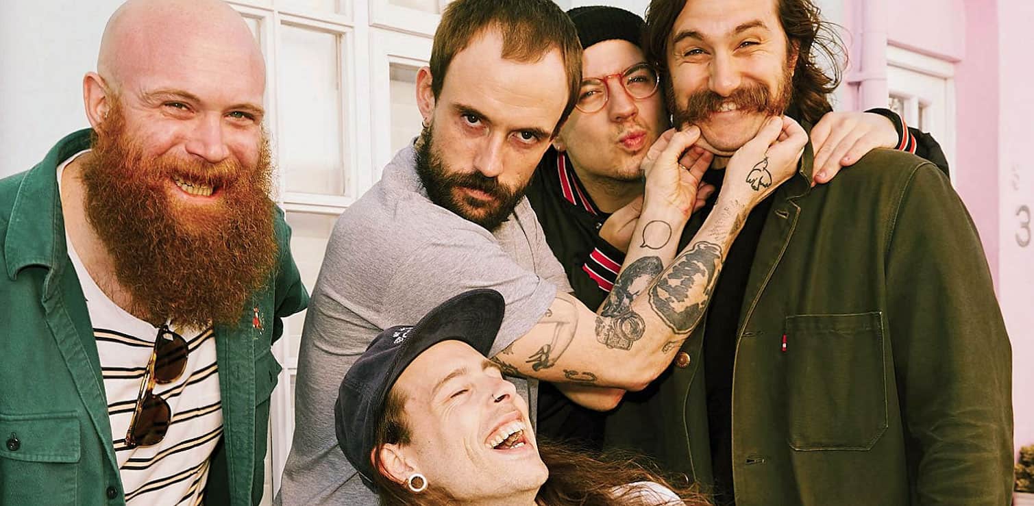 Happy group of friends with tattoos, beards, and casual attire enjoying a joyful moment together at Past Daily, a sound archive of news, history, and music.