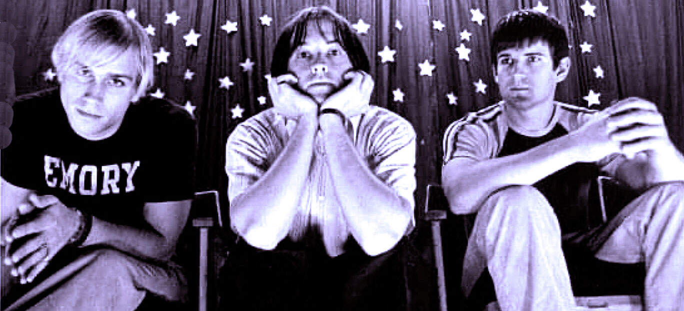 Emory band members sitting in a retro music venue with starry background, showcasing a nostalgic scene from a past music era, emphasizing music history and vintage concert atmosphere.