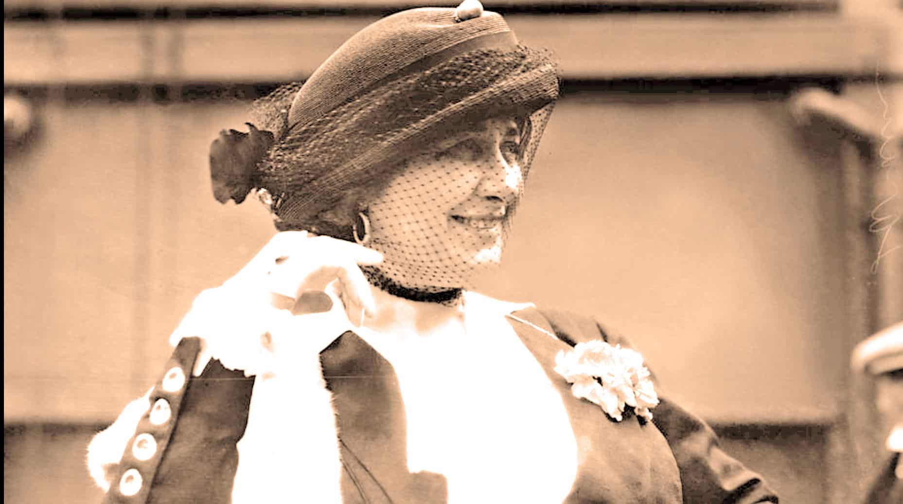 Vintage woman wearing a hat and polka dot veil, smiling in a classic black and white photograph, capturing a nostalgic moment in history, related to music, news, and cultural archives.