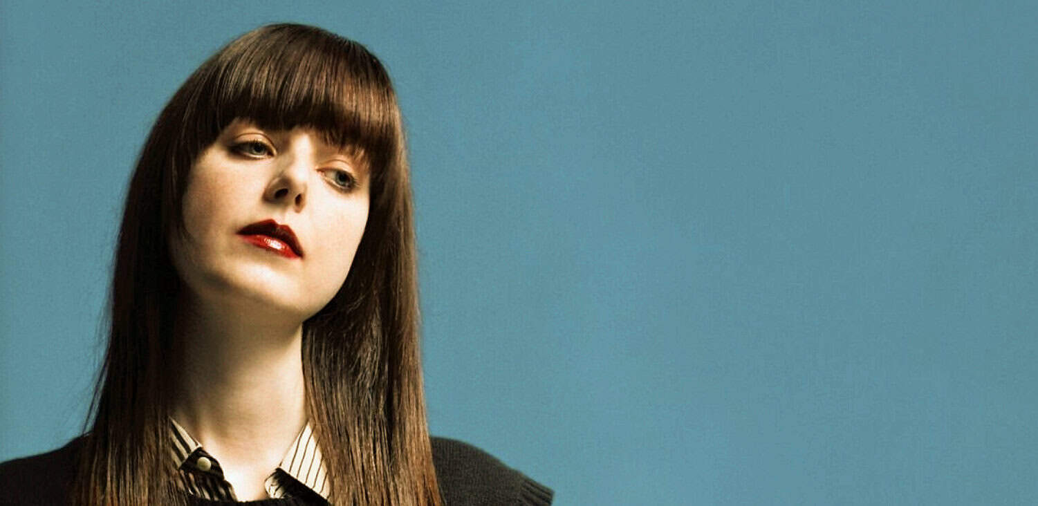 Vintage woman with brown hair and red lipstick against a solid blue background, representing music, news, and historical archives.