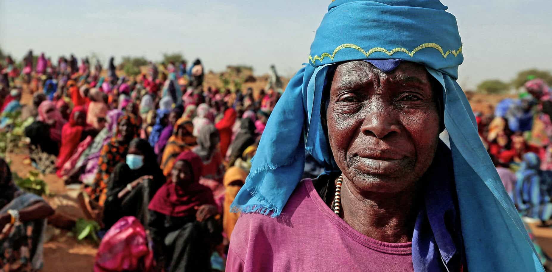 Women in traditional attire attending a community gathering in a rural African setting, captured for historical and cultural documentation.