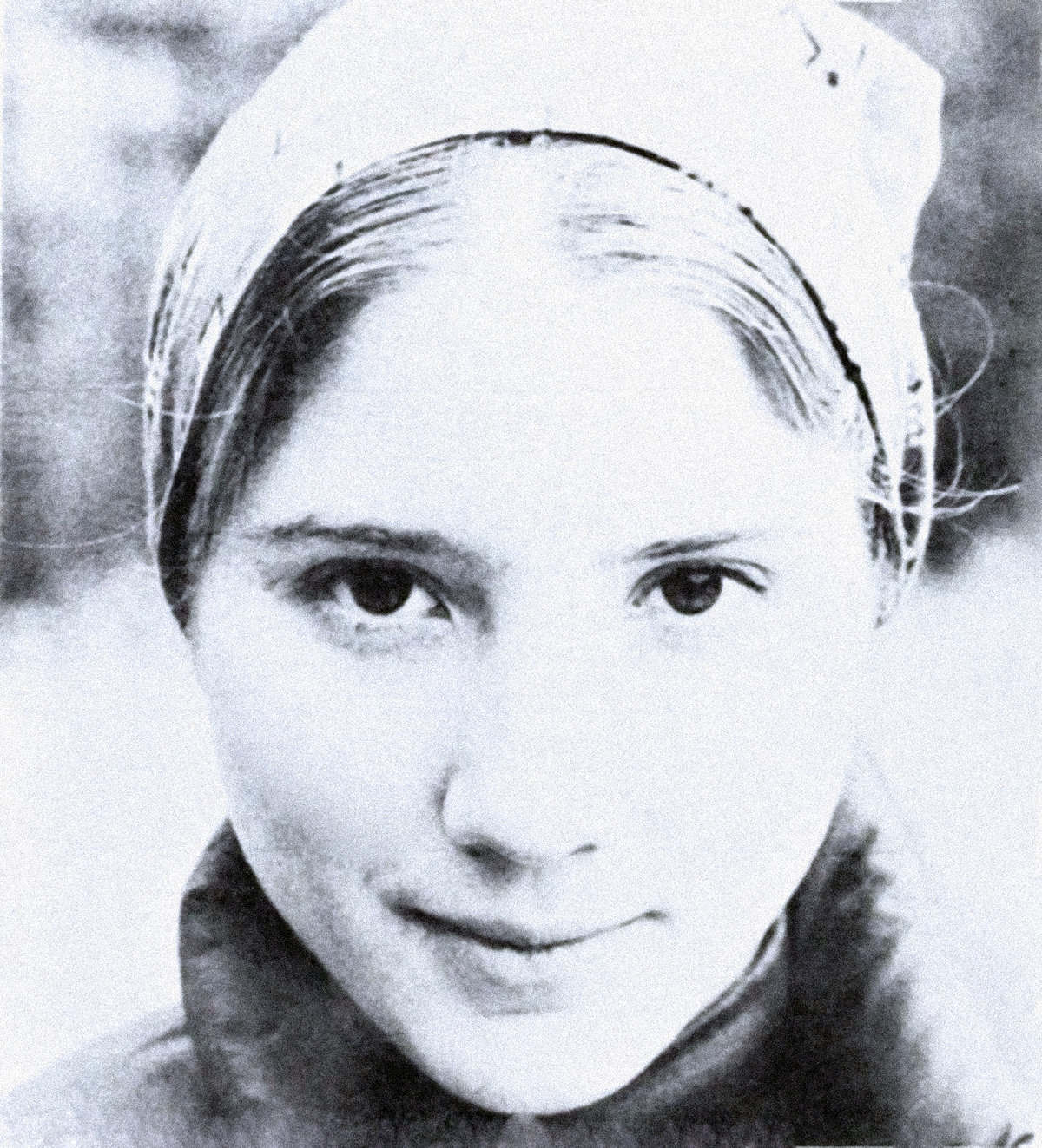 Vintage black and white photo of a young woman with a gentle smile, wearing a headscarf, representing historical news and cultural archives.