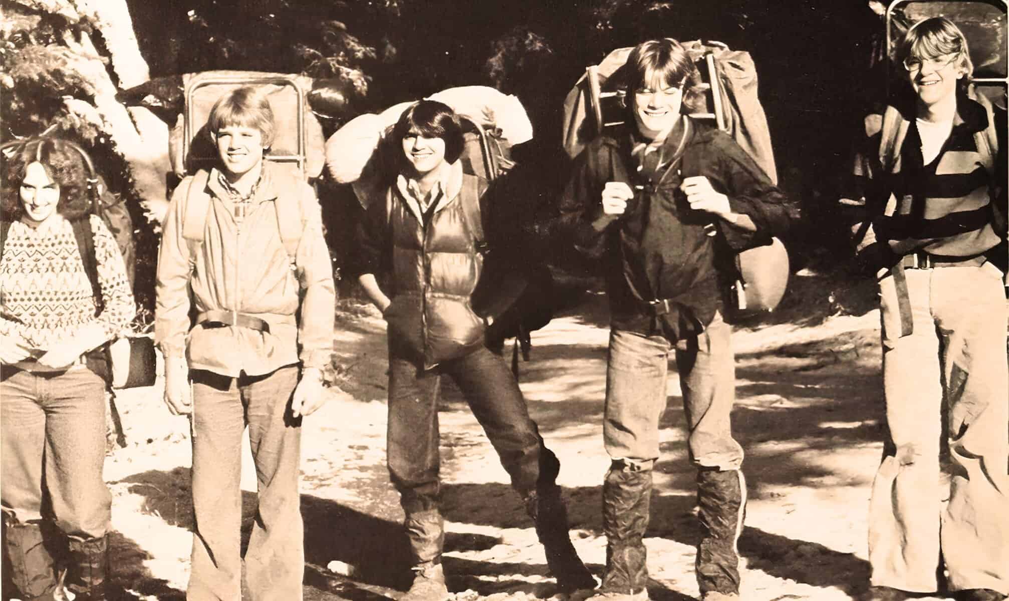 Hikers with backpacks on trail, vintage black and white photo emphasizing outdoor adventure, travel, and nature exploration.
