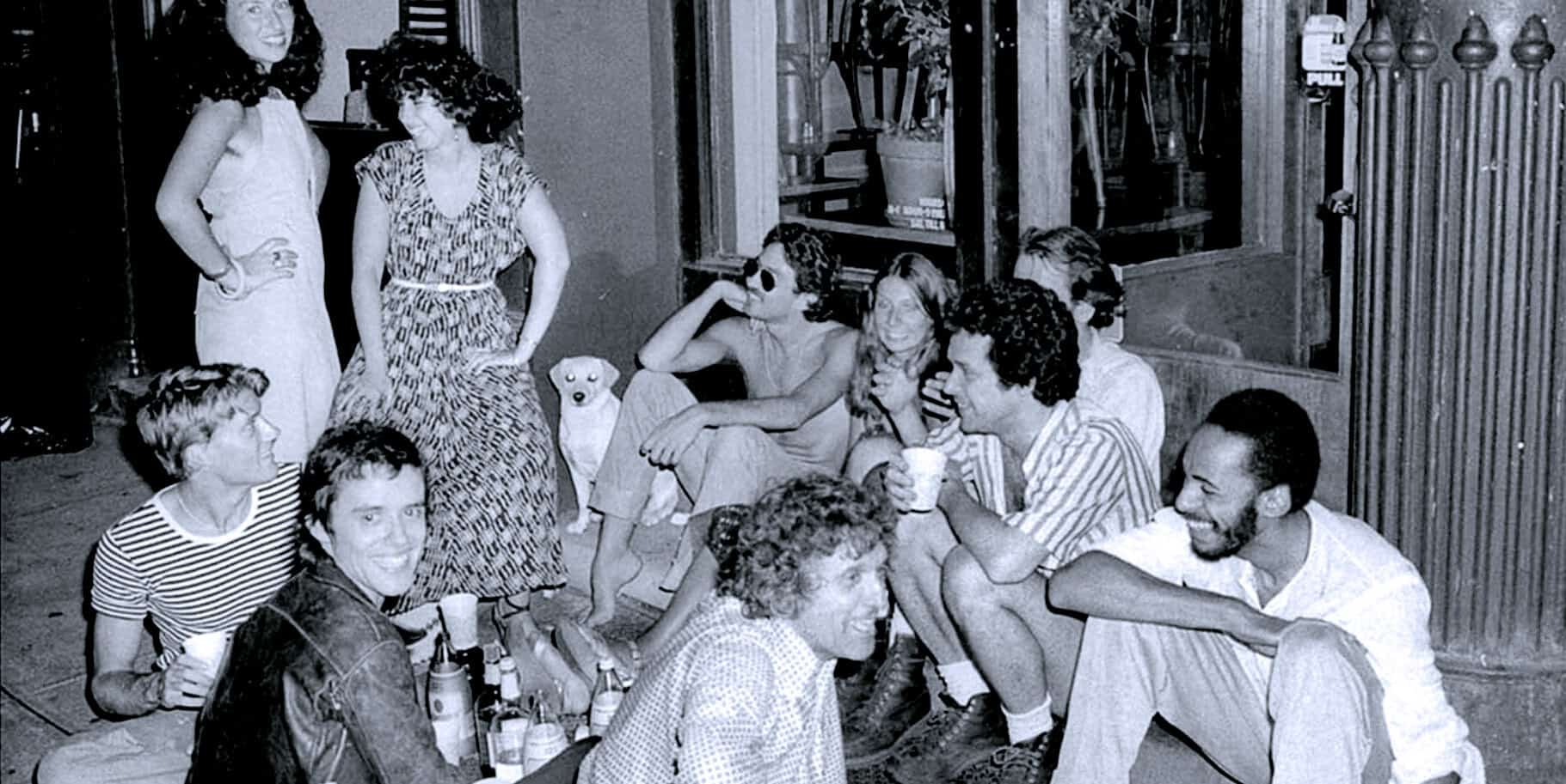 Group of young people having fun socializing, enjoying drinks, and laughing at a casual gathering in a cozy indoor setting, capturing an energetic and joyful moment.
