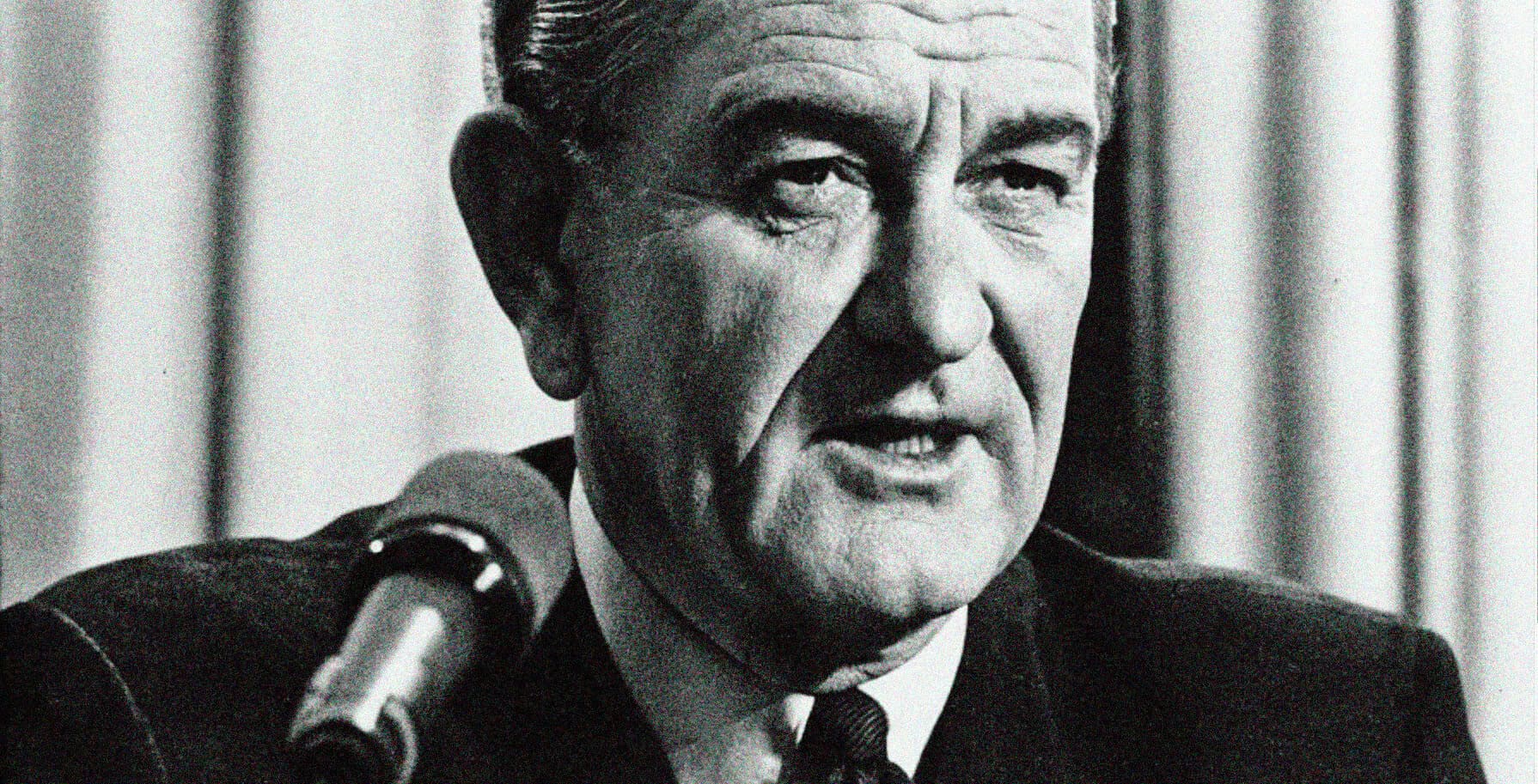 Close-up black-and-white image of a man speaking into a microphone, emphasizing news, history, and music audio archives.