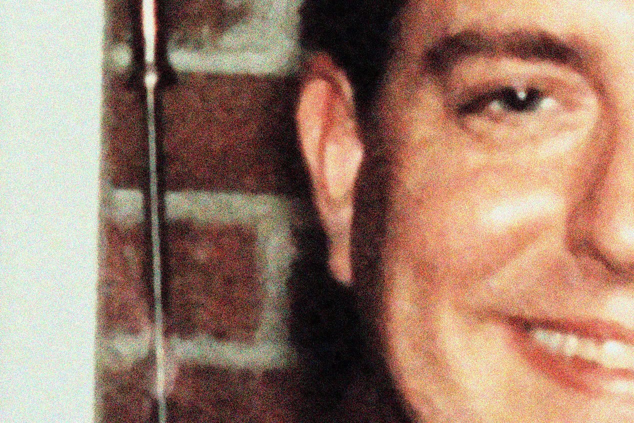 Close-up of a woman's face smiling, highlighting her eye and cheek, against a background featuring a brick wall, representing nostalgic news, history, and music archives.