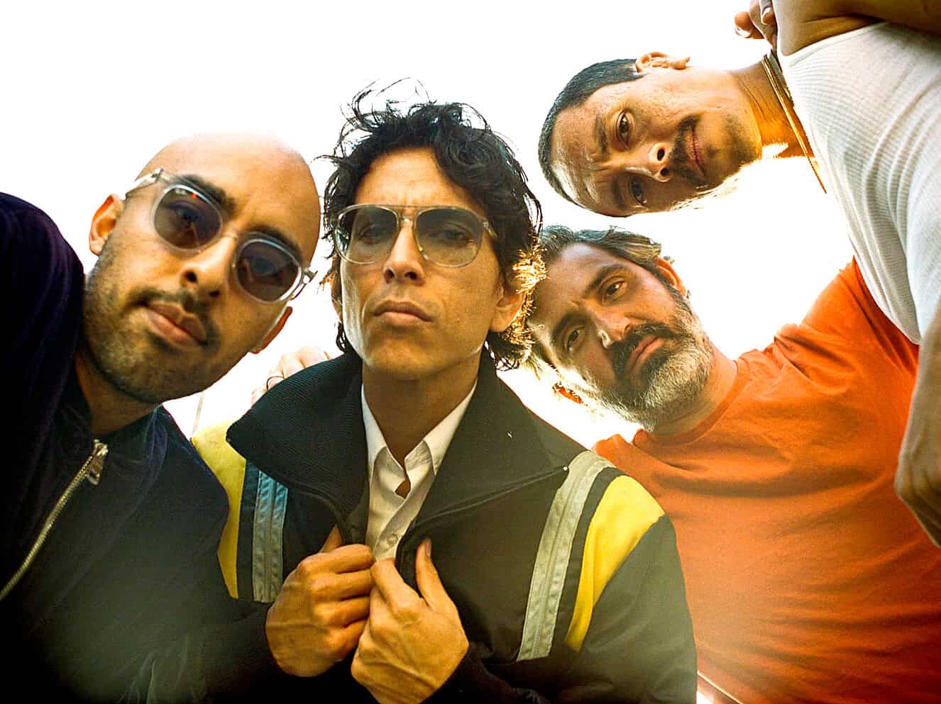 Photo of five men with guest looks in casual clothing, sunglasses, and serious expressions, illustrating a music group or band, capturing the vibe of 90s rock or pop scenes, relevant for music history and cultural archives.