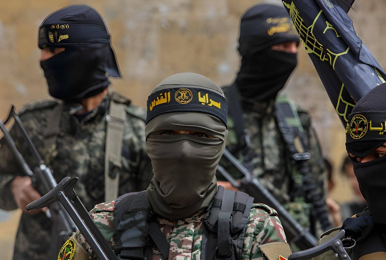 Armed military personnel wearing camouflage and face masks, with weapons, in a desert setting, representing security forces.