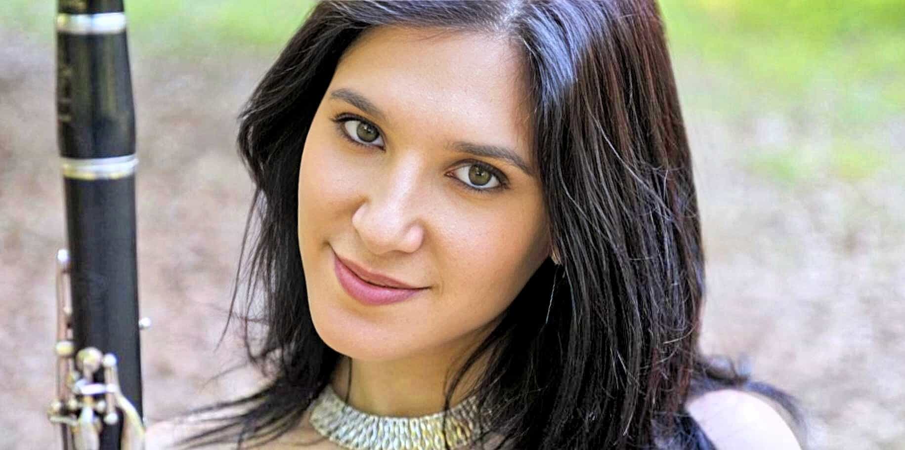Beautiful woman with green eyes and dark hair holding a flute outdoors, showcasing appreciation for music and history.