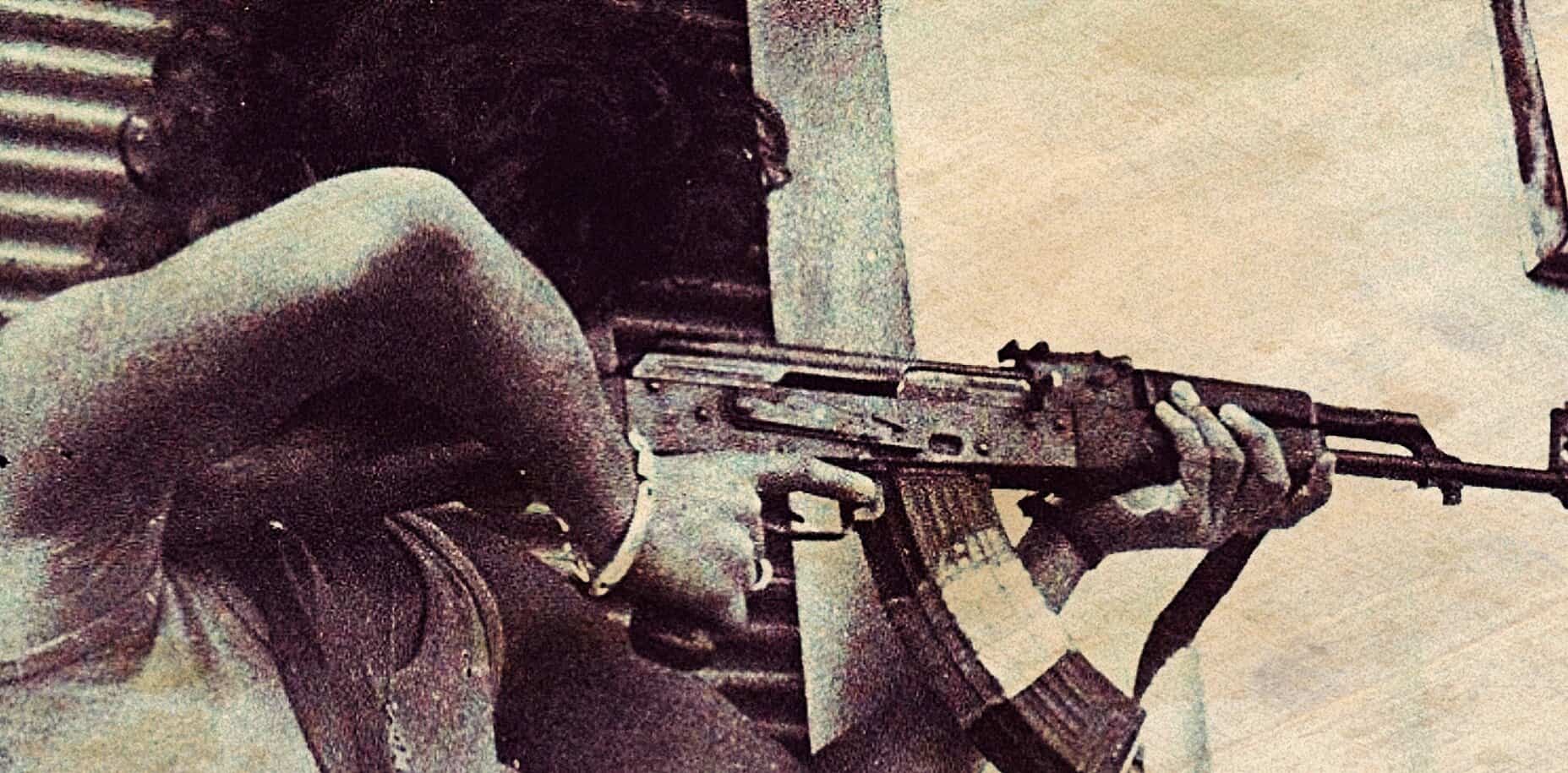 A woman with curly hair aiming a rifle, capturing a moment related to historical news and political conflicts, representing themes of war, history, and media coverage for the sound archive.