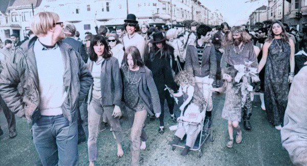 A diverse group of people walking on a city street, capturing a candid moment of urban life with casual fashion and varied ages.