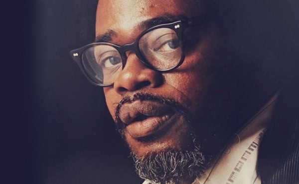 Close-up of an African American man with glasses, highlighting historical news, music, and sound archive themes at Past Daily.