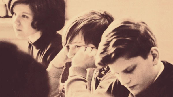 Vintage black and white photo of young students in a classroom, focusing on history, music, news, and educational archives.