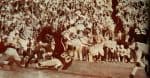 Vintage football game in action with players in classic uniforms and a spirited crowd in the background, capturing the excitement of historic sports events.