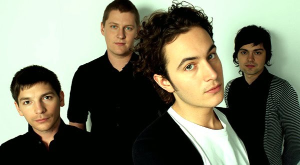 2010s indie rock band members, young men with dark clothing, in studio portrait for music history and archive features.