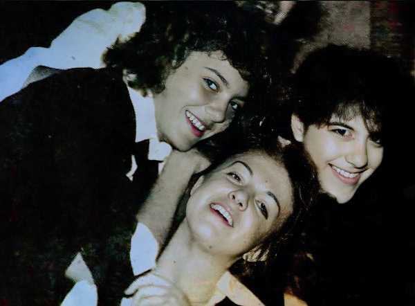A vibrant, nostalgic image of three young women with curly and straight hair smiling together, capturing a joyful moment, perfect for themes of friendship, music, and historical memories.