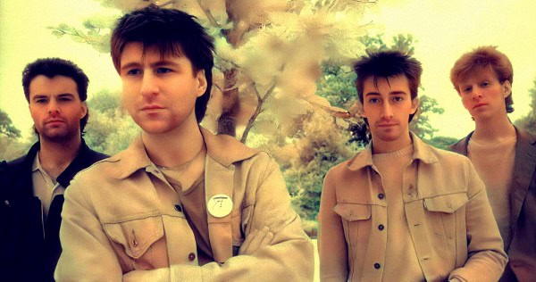 Vintage indie band members posing outdoors with trees in background, promoting retro music and sound archives.