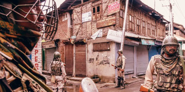 Armed soldiers patrolling an urban street during a conflict, showcasing security issues and violence in the area.