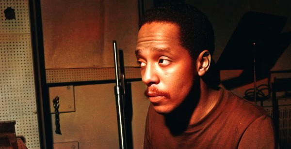 A young man in a sound recording studio, focused on audio equipment for news, music, and history archives.