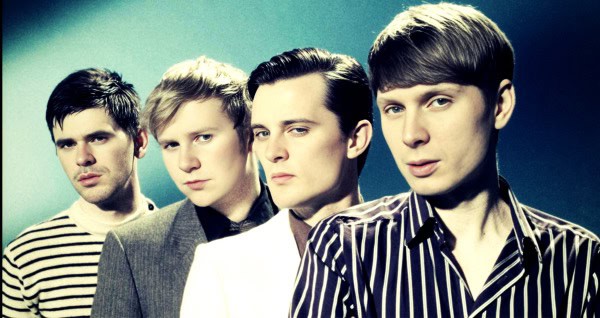 Music band members in stylish attire posing for a promotional photo.