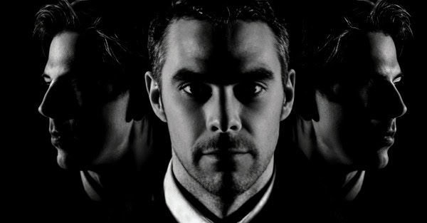 Mysterious men's portrait in black and white with reflective shadows, artistic photography for historical and music archive websites.