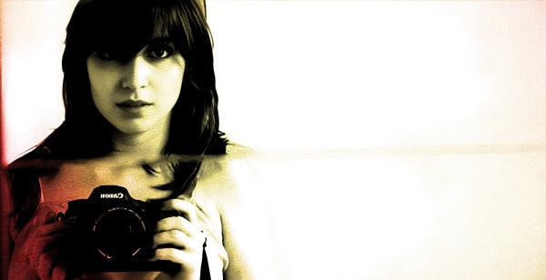 Vintage black and white photo of a young woman holding a camera, emphasizing photography and media.